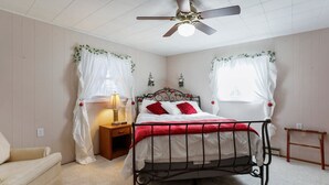 Une chambre à coucher avec un lit, une table de chevet, une lampe et un ventilateur de plafond.