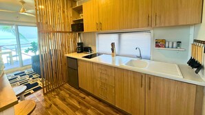 Une cuisine de taille réduite, dotée de meubles en bois, d’un plan de travail blanc et d’un évier encastré.