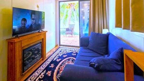 Un salon équipé d’un téléviseur à écran plat, d’un canapé et d’un tapis à motifs.