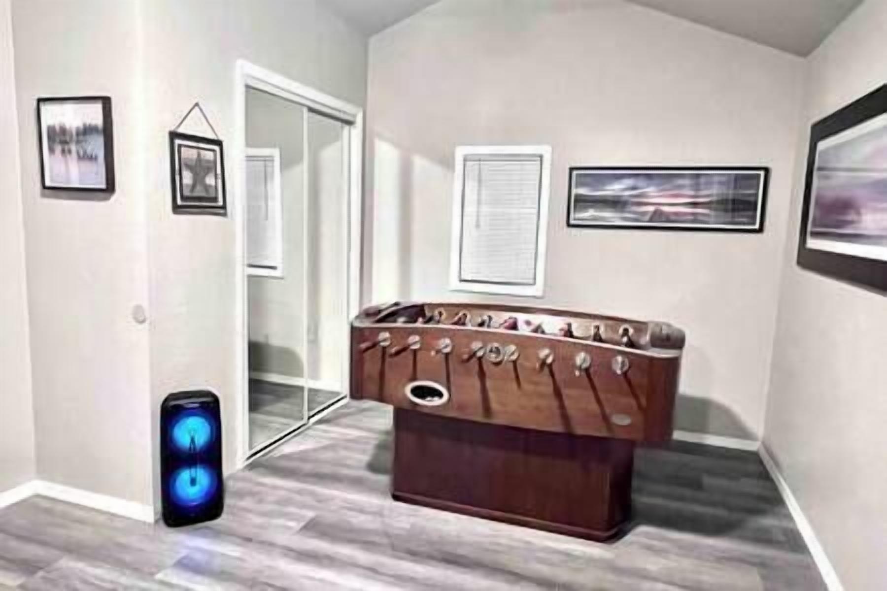 A room with a foosball table, a door, and framed pictures on the walls.
