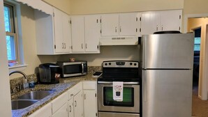 A kitchen with white cabinets, a stainless steel refrigerator, a microwave, an oven, and a sink. - Stock Cottage Cozy 2 BR, 2 Bath House next to Biology Trails and SAU (Ooltewah)