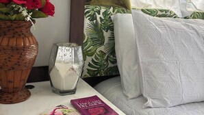Una mesita de noche ordenada con un jarrón de rosas rojas, una vela y un libro.
