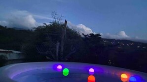 Una piscina con luces de colores y vistas del paisaje circundante.