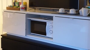 A modern kitchen with a built-in microwave, oven, and a flat-screen TV.
