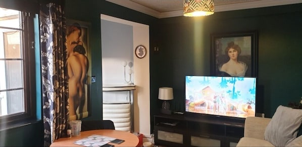 A living room with a television, a dining table, and a sofa.