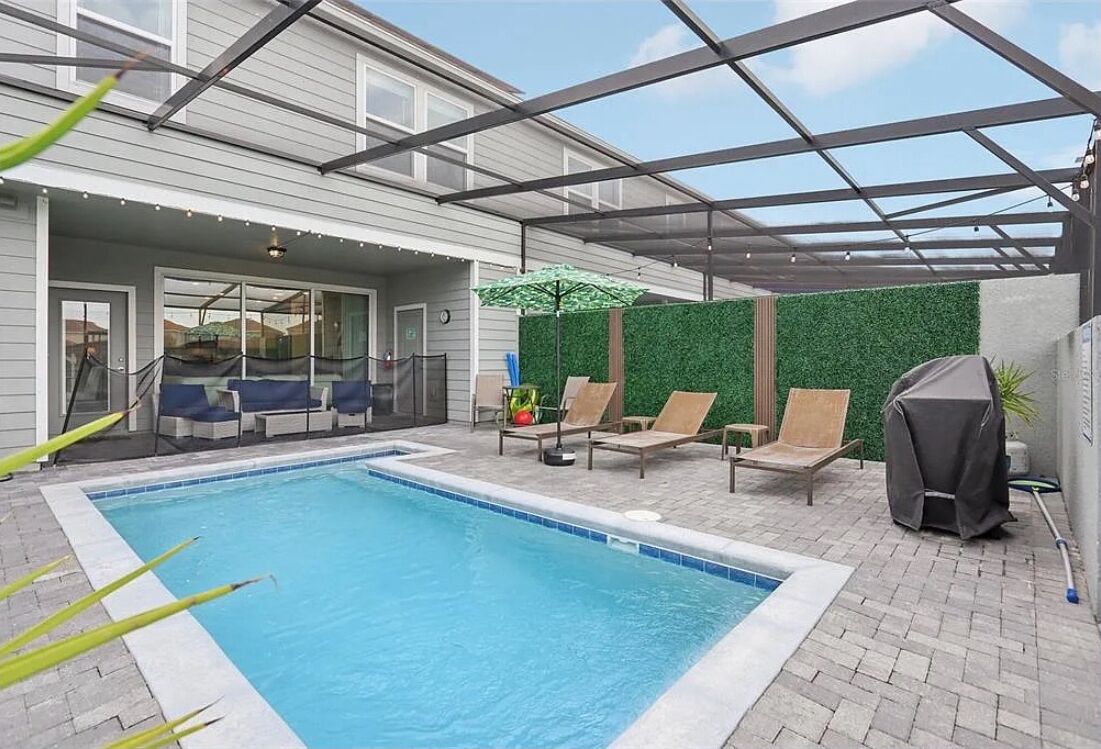 Ein Swimmingpool mit Liegestühlen und einer überdachten Terrassenanlage.