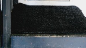 Une porte de couleur beige, dotée d’un trou de serrure et d’une petite fenêtre.