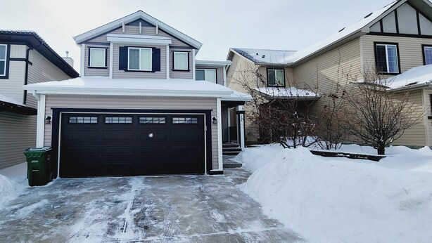 Un quartier résidentiel avec des maisons, un garage et de la neige accumulée.