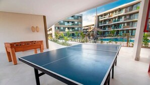 Mesa de ping pong en un espacio exterior con vistas a edificios modernos y una piscina.