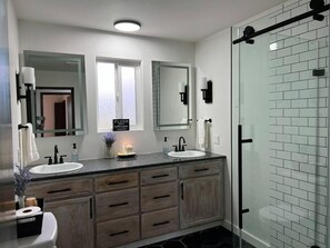 Ein modernes Badezimmer mit zwei Waschbecken, einem Waschtisch und einer Duschkabine.