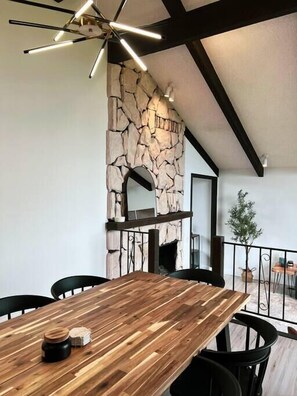 Ein Essbereich mit Holztisch, Steinwand und einer modernen Kronleuchter.