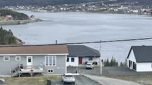 A coastal residential area with houses, a road, and a large body of water. - Harbour Hutch  (St. Anthony)