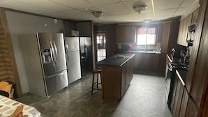 A kitchen with a central island, built-in appliances, and a dining area with a table and chairs. - Harbour Hutch  (St. Anthony)