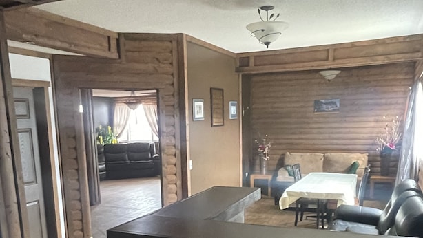 A log cabin interior with a reception desk, a dining area with a table and chairs, and a living room with a sofa and a fireplace. - Harbour Hutch  (St. Anthony)