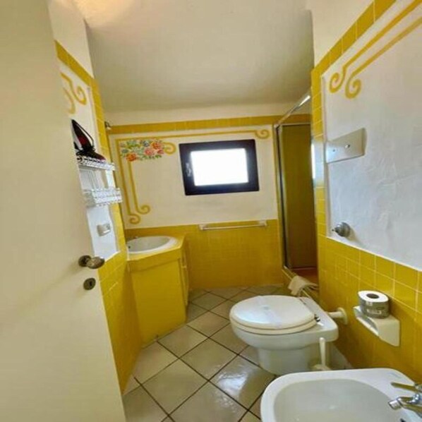 A small bathroom with a toilet, sink, and a window.