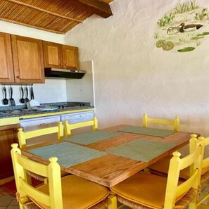 Una cocina con armarios de madera, una estufa y una mesa de comedor con sillas.
