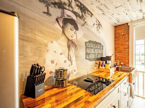 A kitchen with a wooden countertop, a knife block, a coffee machine, and a wall mural.