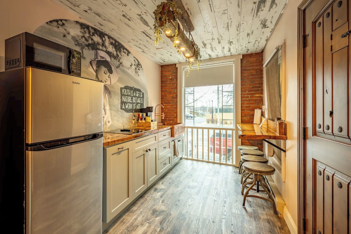 A kitchen with a Galanz refrigerator, wooden cabinets, a large window, and a view of the outside.