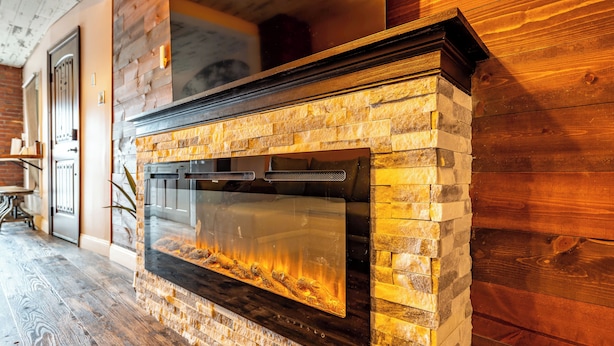 A stone fireplace with a glass front, set in a wooden wall. - BurgBnB Downtown (Harrisburg)