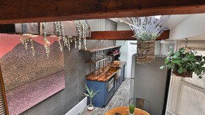 A compact kitchen with a wooden countertop, hanging plants, and a small dining table. - BurgBnB Downtown (Harrisburg)