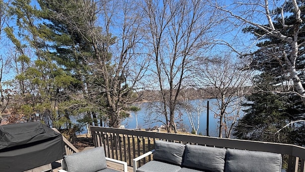 A deck with outdoor furniture, a grill, and a view of a lake and trees. - Private Lake Home, Game Room & Pontoon Rental on Keewahtin Lake (Forest Lake)