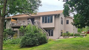 A two-story house with a covered balcony, a staircase, and a well-maintained lawn. - Private Lake Home, Game Room & Pontoon Rental on Keewahtin Lake (Forest Lake)