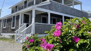 A two-story house with a porch and a covered front porch area. - Oceanfront Family Retreat in Scituate with Private Beach, Expansive Porches, Outdoor Shower (Scituate)