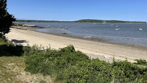 Ein Strand mit Booten, blauem Himmel und Hügeln in der Ferne.