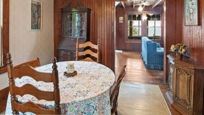 Ein Esszimmer mit Holzboden, einem runden Tisch, Stühlen und einem Schrank.