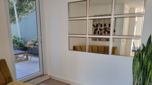 A room with a sliding glass door leading to an outdoor area, a yellow armchair, a wall-mounted mirror, and a potted plant. - Stylish ground floor double w/ ramp acces and balcony. (La Ceiba)