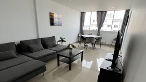 A modern living room with a grey sectional sofa, a coffee table, and a TV stand. - Super 4 Rooms refurbished (Villeurbanne)