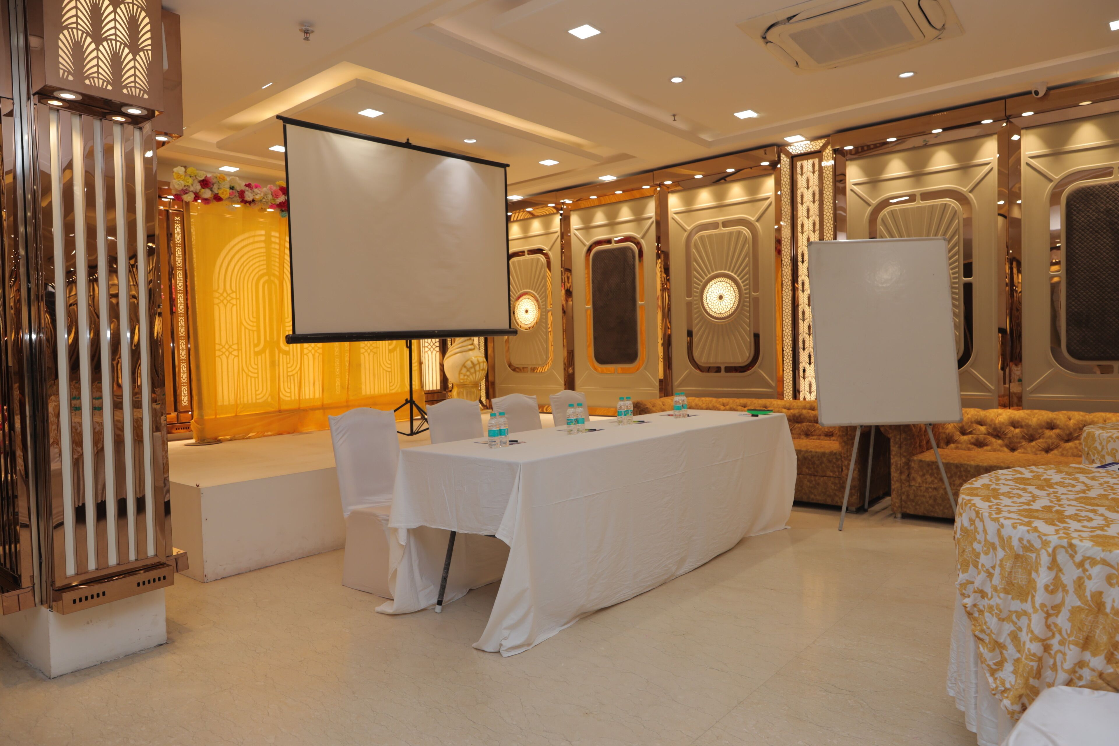 A conference room with a long table, white chairs, and a large screen.