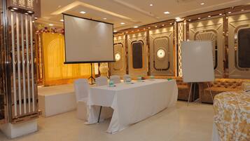 A conference room with a long table, white chairs, and a large screen.
