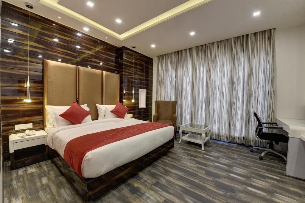 A modern hotel room with a large bed, a desk, and a chair.