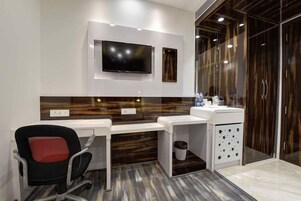 A modern office space with a desk, chair, and a television mounted on the wall.