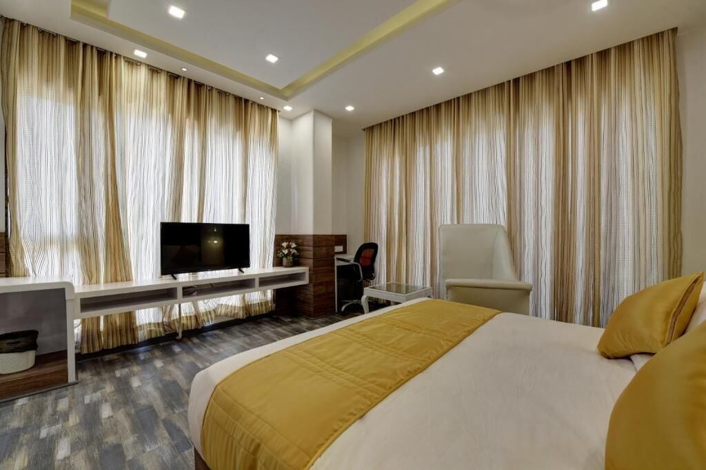 Una camera d'albergo con un letto grande, una scrivania con un computer, una TV e tende.