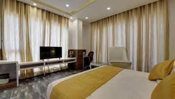 Una camera d'albergo con un letto grande, una scrivania con un computer, una TV e tende.