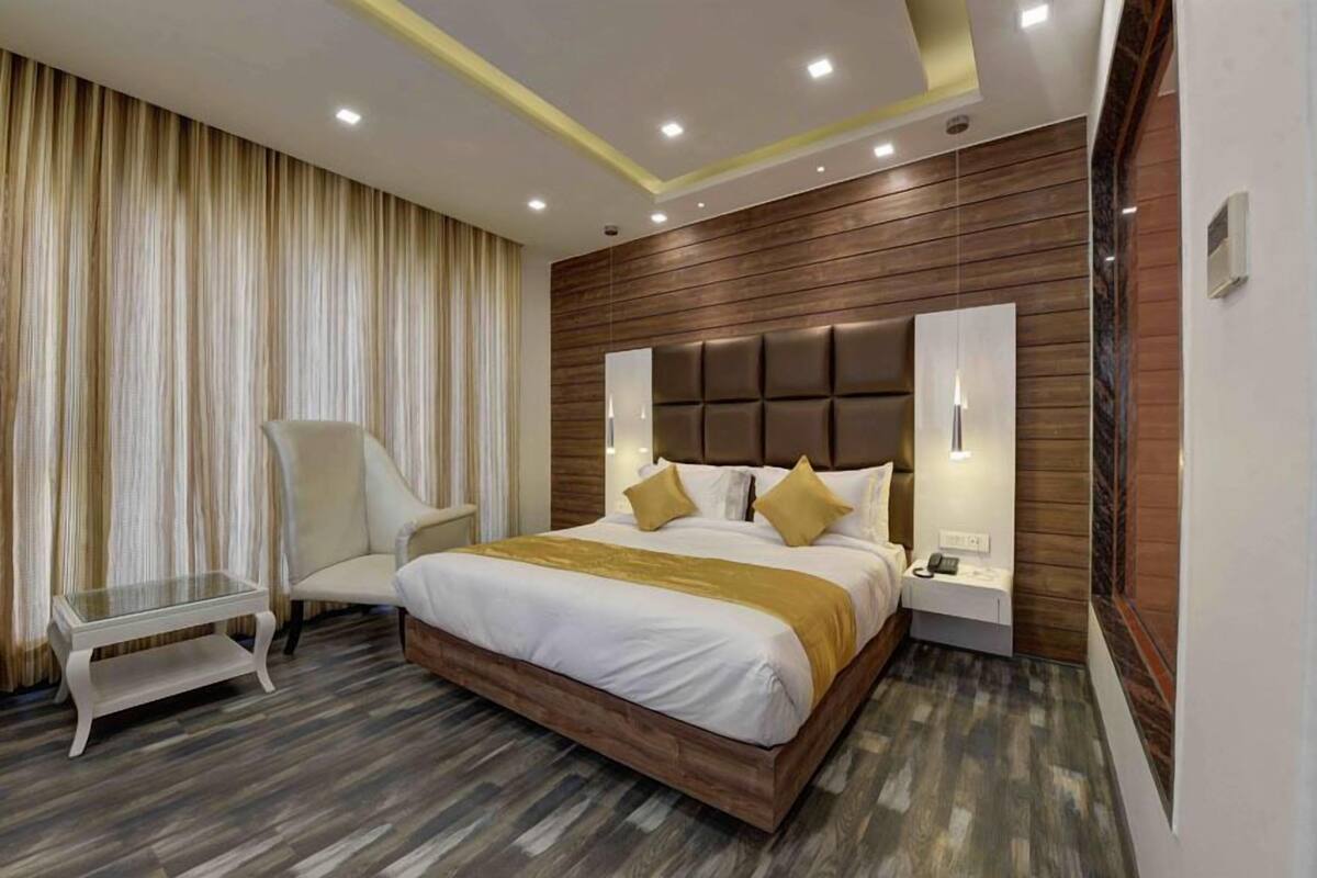 Una habitación de hotel moderna con una cama grande, una mesita de noche, una silla y un buró.
