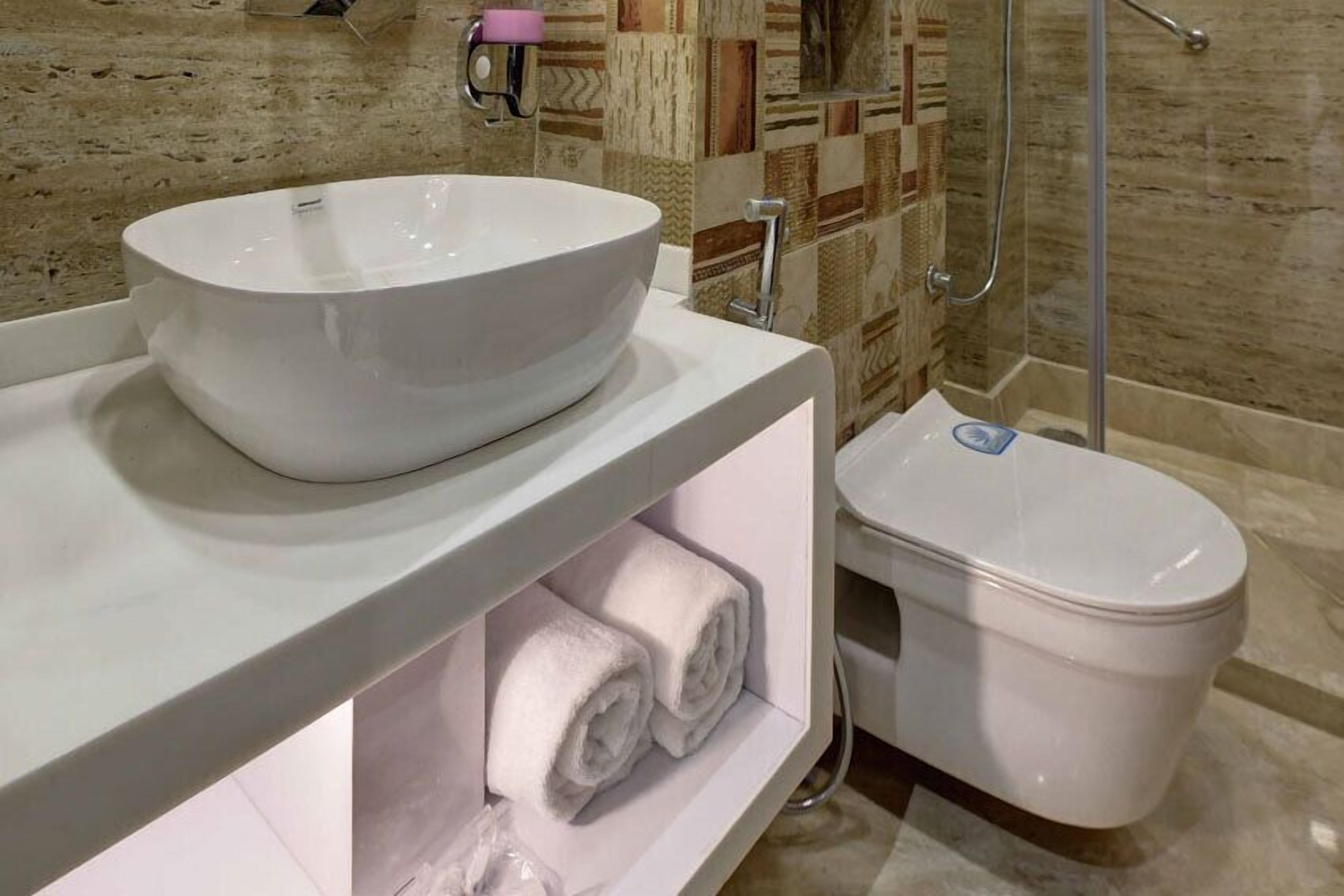 A bathroom with a large white sink, a toilet, and a shower area.