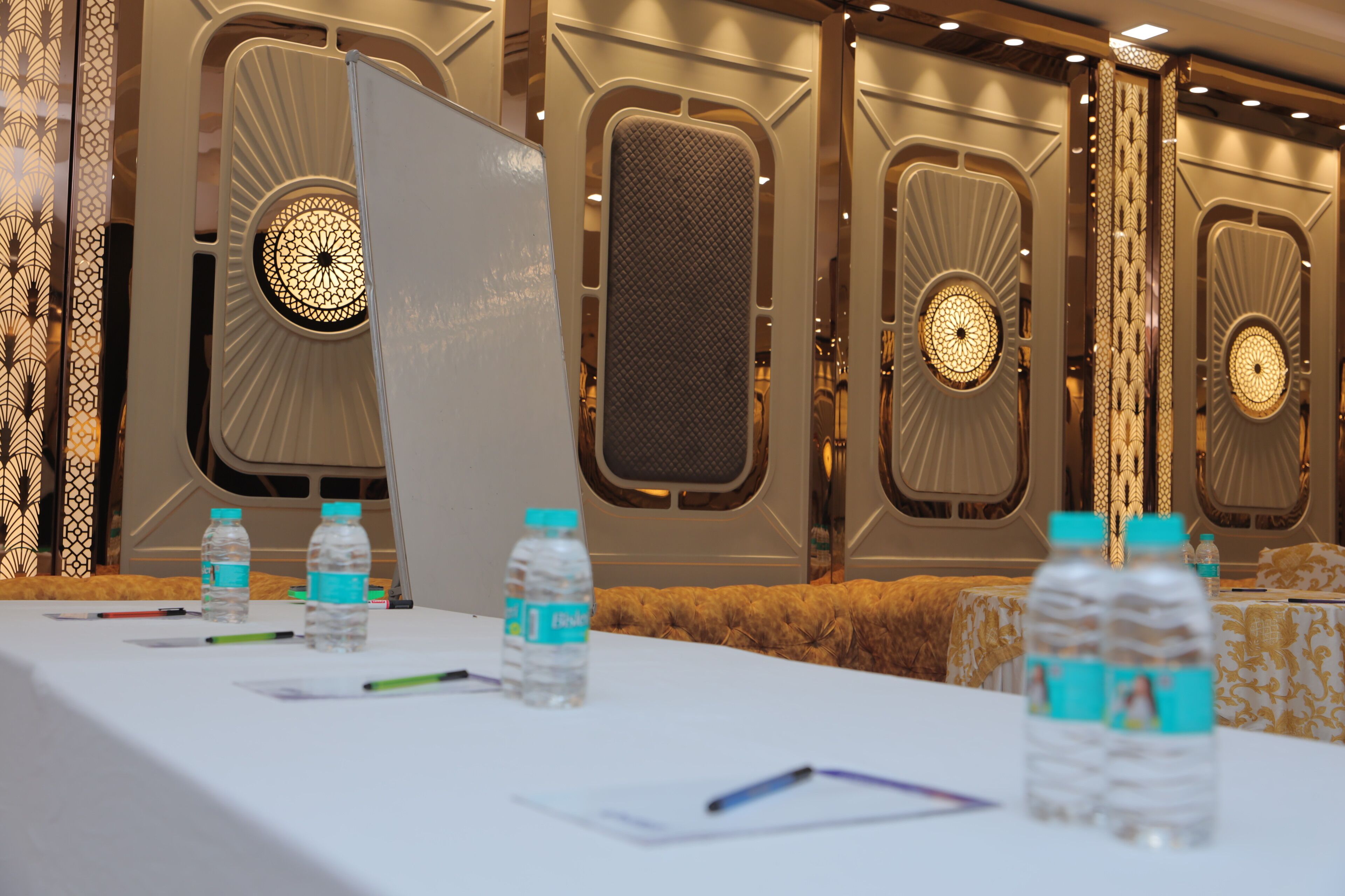 Un salón de conferencias con una larga mesa, botellas de agua y una computadora portátil.