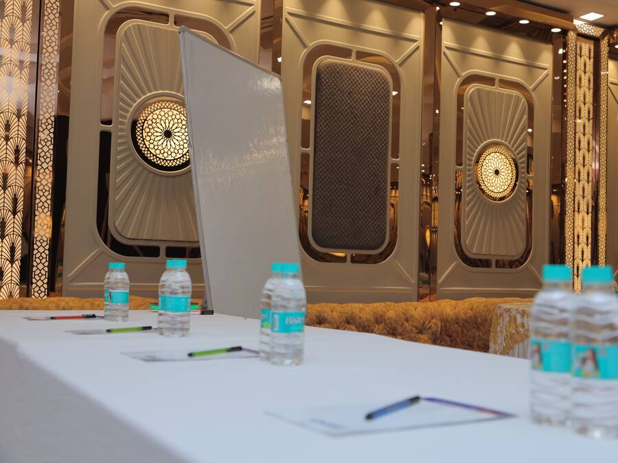 Uma sala de conferência com uma mesa comprida, garrafas de água e um laptop.