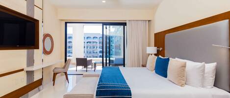 Une chambre d’hôtel dotée d’un grand lit, d’un téléviseur à écran plat, d’un ventilateur de plafond, d’un bureau et offrant une vue sur la ville depuis les portes du balcon.