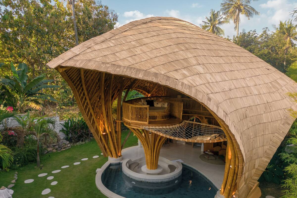 Una estructura de bambú con una zona de estar circular y una fuente central de agua.