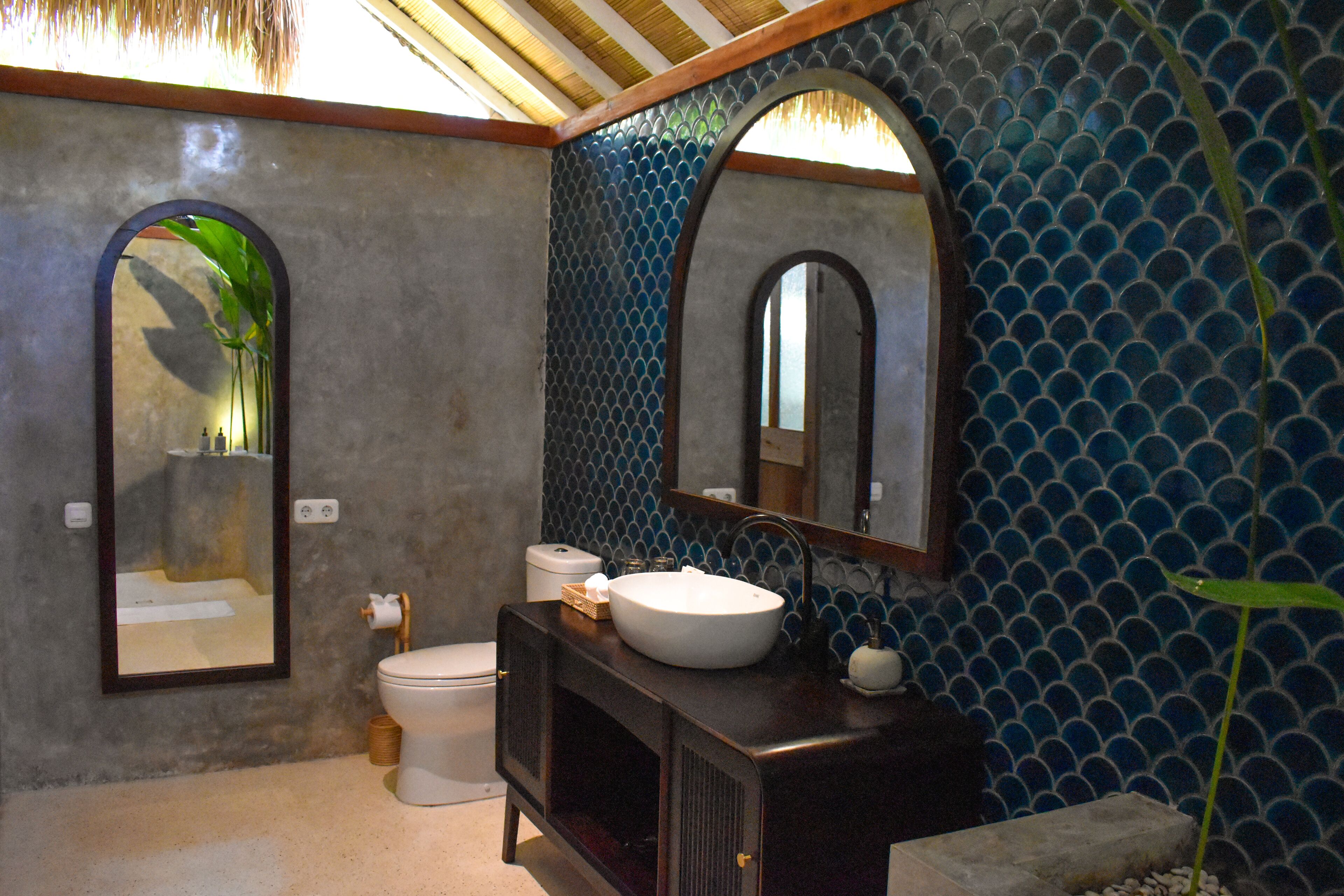 A bathroom with a large mirror, a sink, and a toilet.