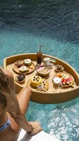 Una bandeja de mimbre con diferentes alimentos y bebidas junto a una piscina.