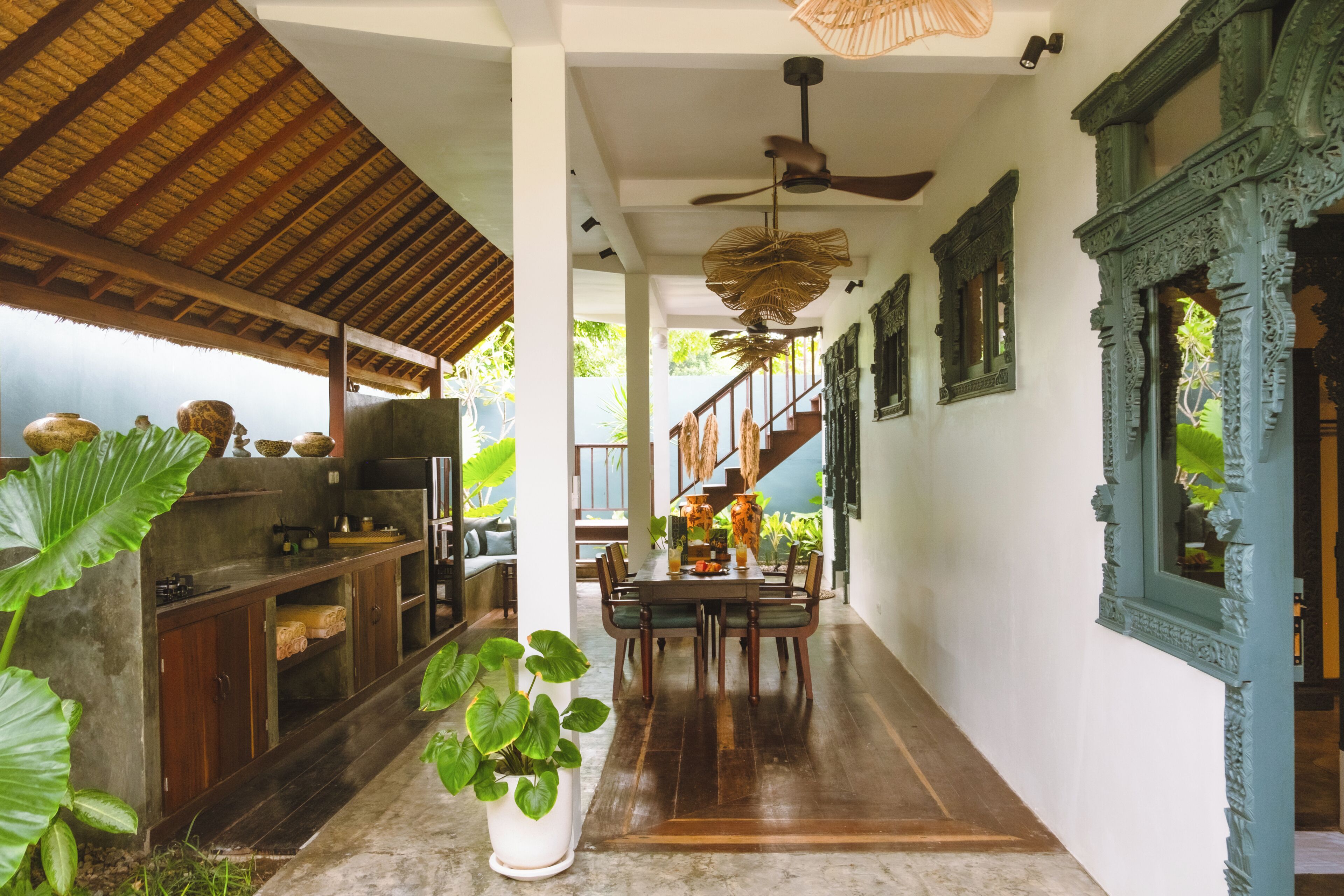A spacious kitchen with a dining area, a ceiling fan, and a staircase leading to an upper level.