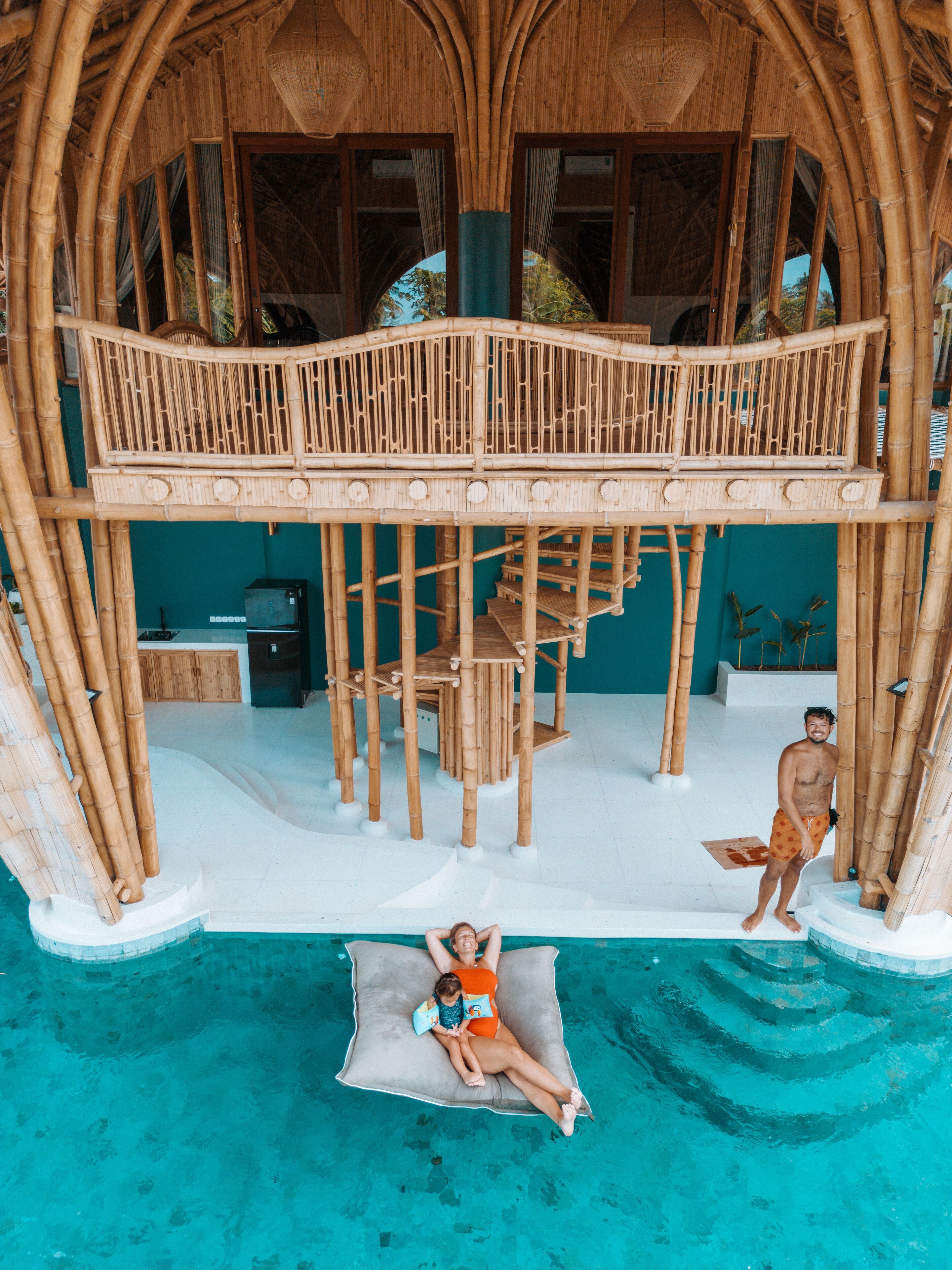 Una estructura de bambú de varios niveles con piscina, una escalera y un área de descanso.