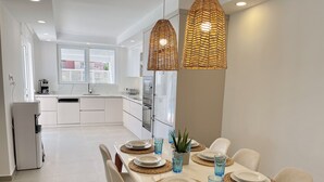 Una cocina moderna con armarios blancos, horno empotrado y cafetera.