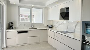 Una cocina moderna con armarios blancos, lavavajillas integrado, cafetera y microondas.