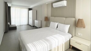 Una habitación de hotel moderna con una cama grande, mesitas de noche, un armario y un equipo de aire acondicionado en la pared.